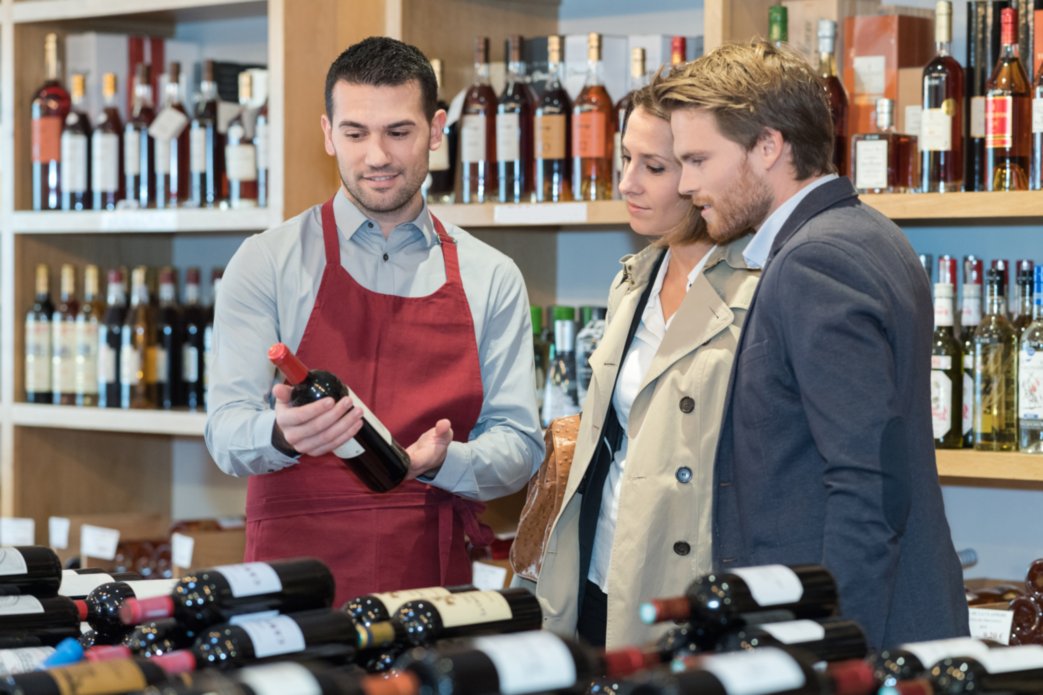 Waiter showing bottles of wine to man and woman